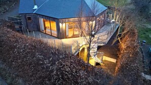 Une maison moderne avec un toit en pente, de grandes fenêtres et un intérieur bien éclairé.