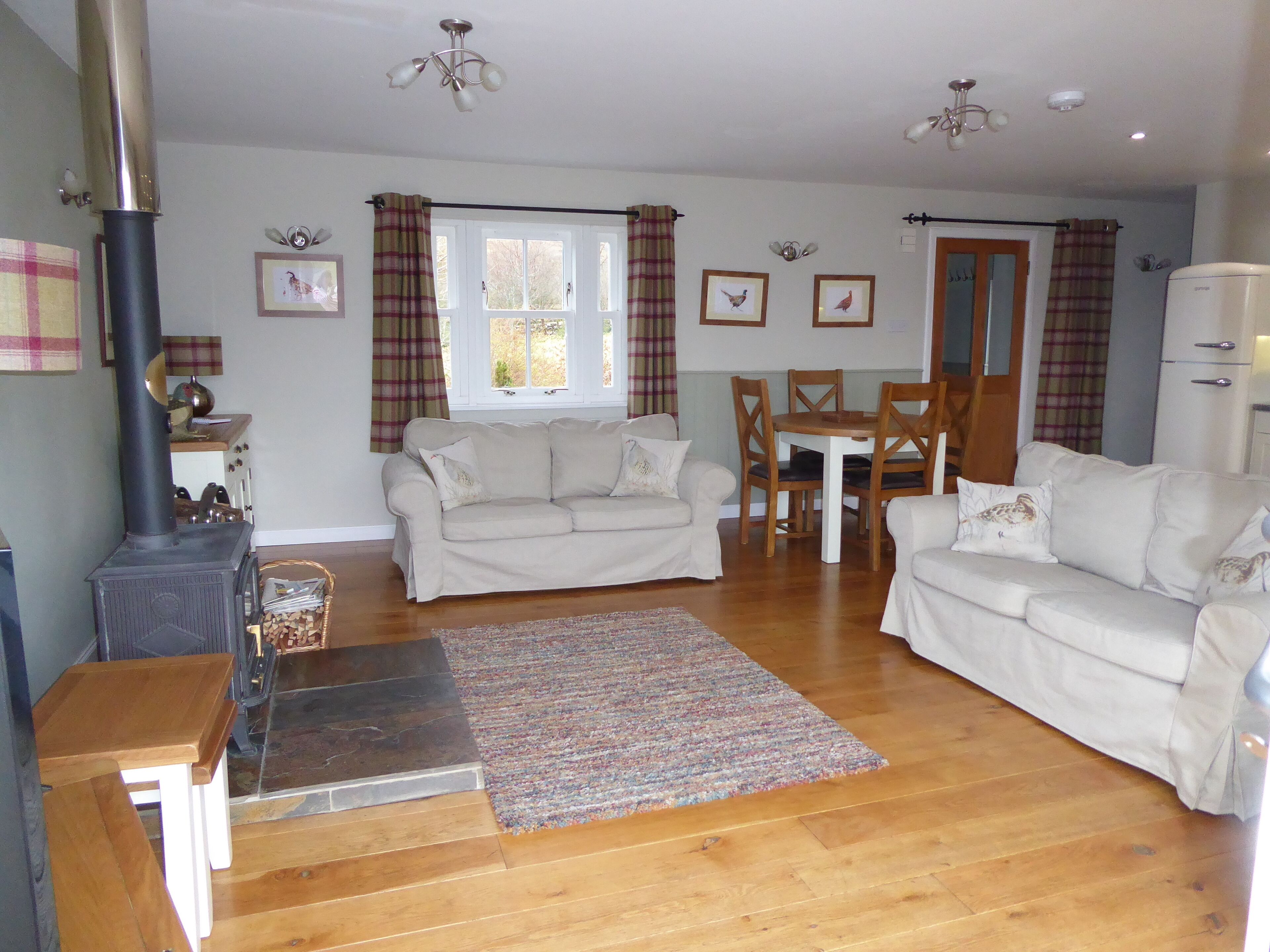 A living room with a sofa, a dining table with chairs, a fireplace, and a window with curtains.