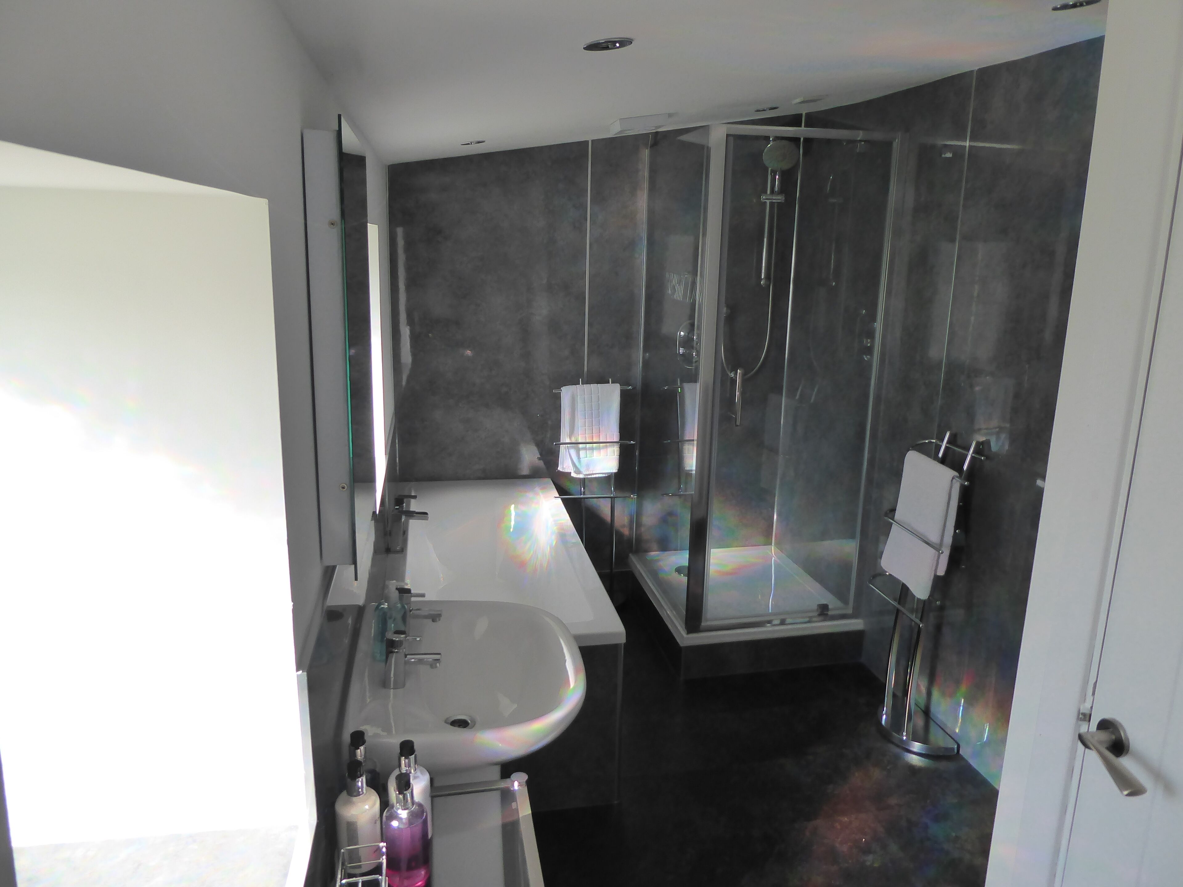 A modern bathroom with a large mirror, a sink, and a shower enclosure.