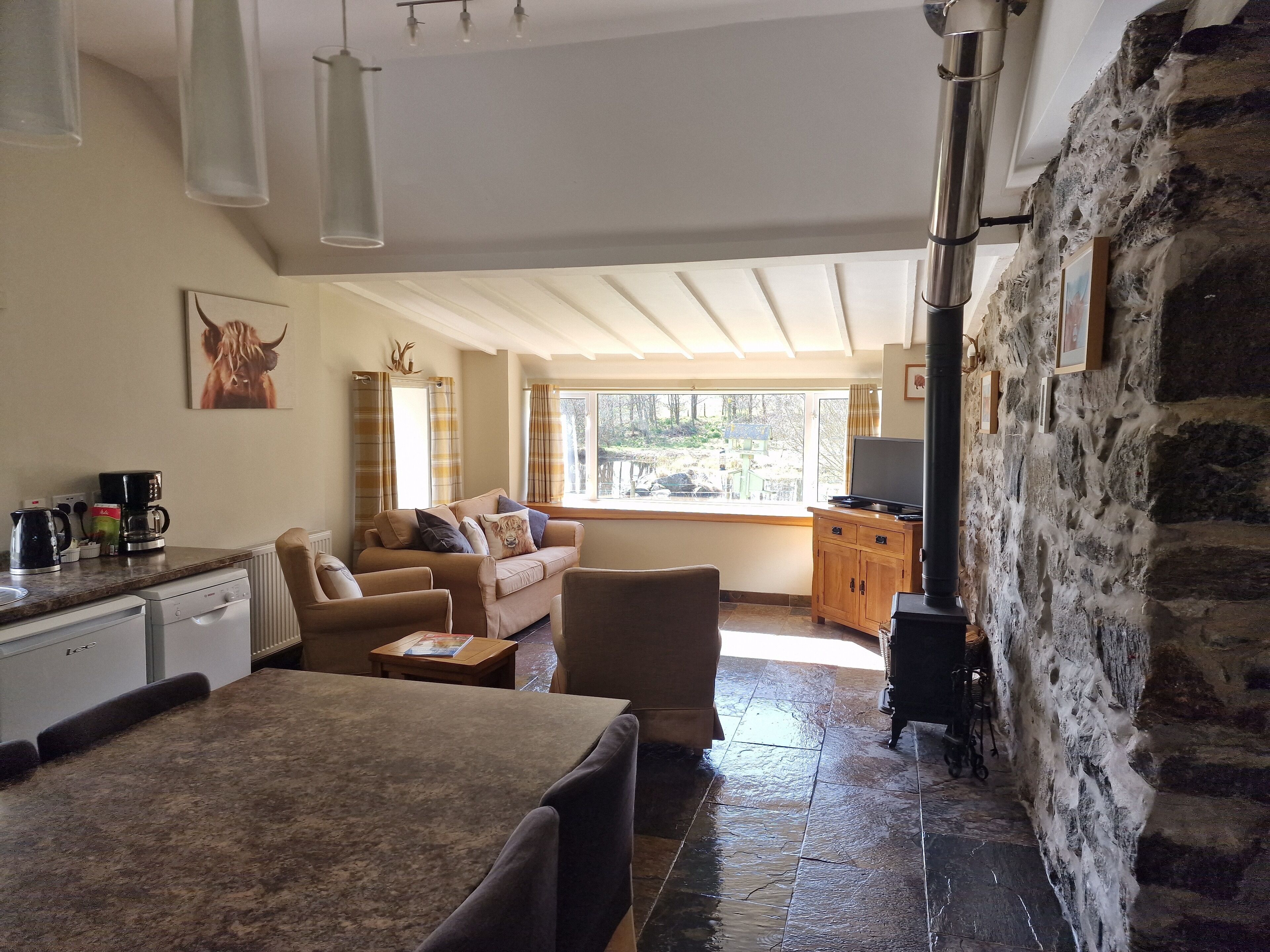 A cozy living area with a sofa, a coffee station, and a television.