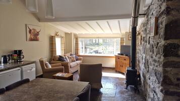 A cozy living area with a sofa, a coffee station, and a television.