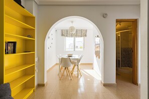 Cozy dining area with a white table and chairs, perfect for meals, and a large arched doorway leading to a separate space.