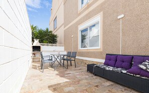 Relax on the patio with a wicker sofa, small table, and two chairs amidst a beautiful stone tile floor.