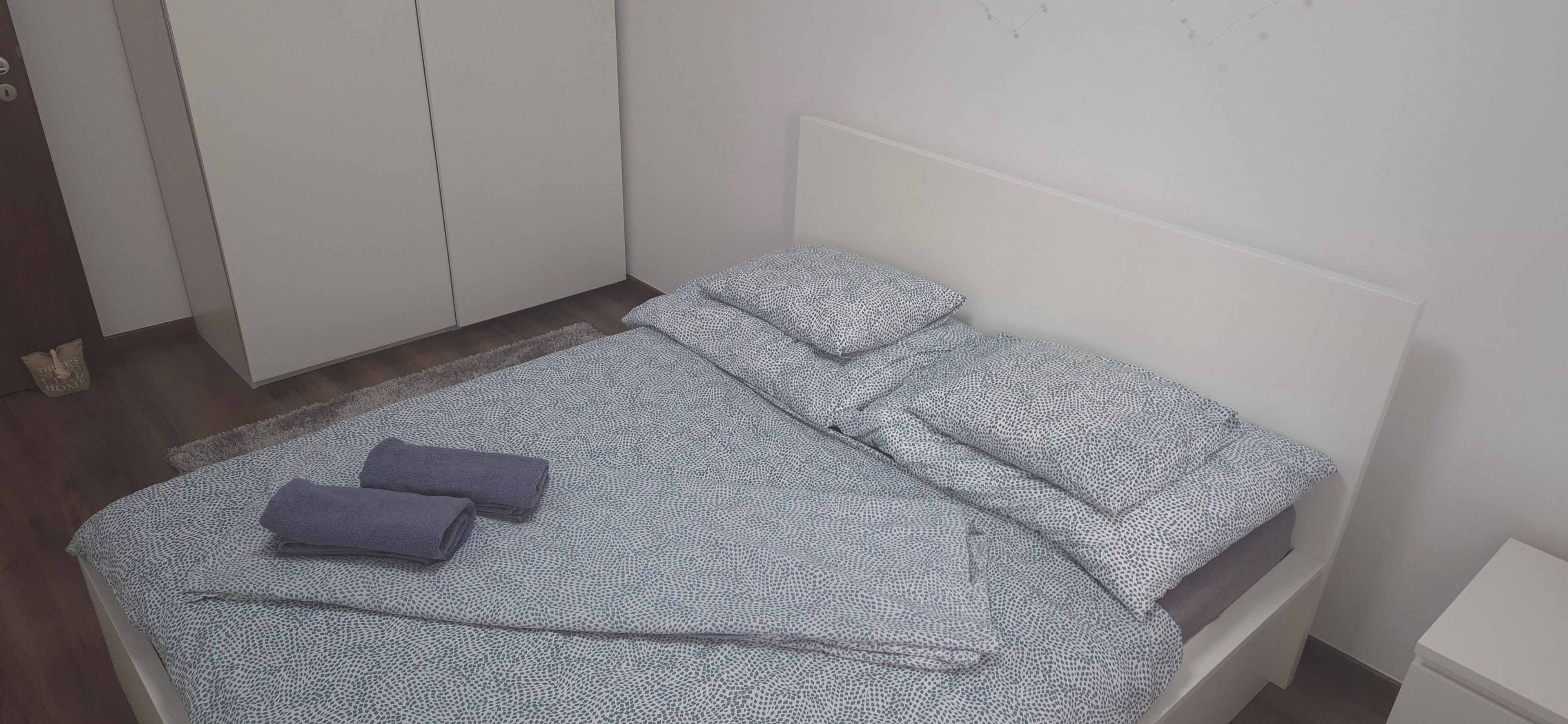A neatly made bed with patterned bedding and two folded towels.