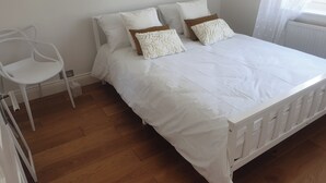 A bedroom with a white bed, white walls, and a wooden floor. - Richmond Retreat A Gem! (Richmond)