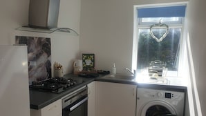 A compact kitchen with a gas stove, oven, sink, and a built-in washing machine. - Richmond Retreat A Gem! (Richmond)