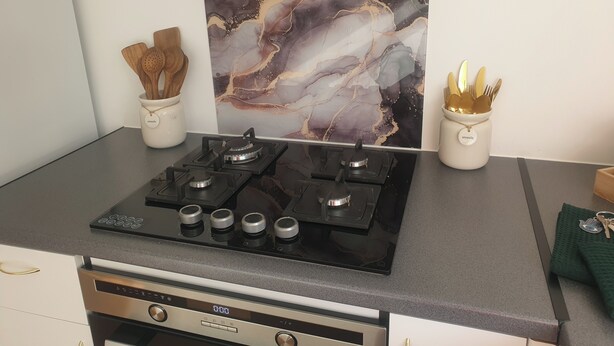 A kitchen with a gas stove, a marble backsplash, and utensils in holders. - Richmond Retreat A Gem! (Richmond)