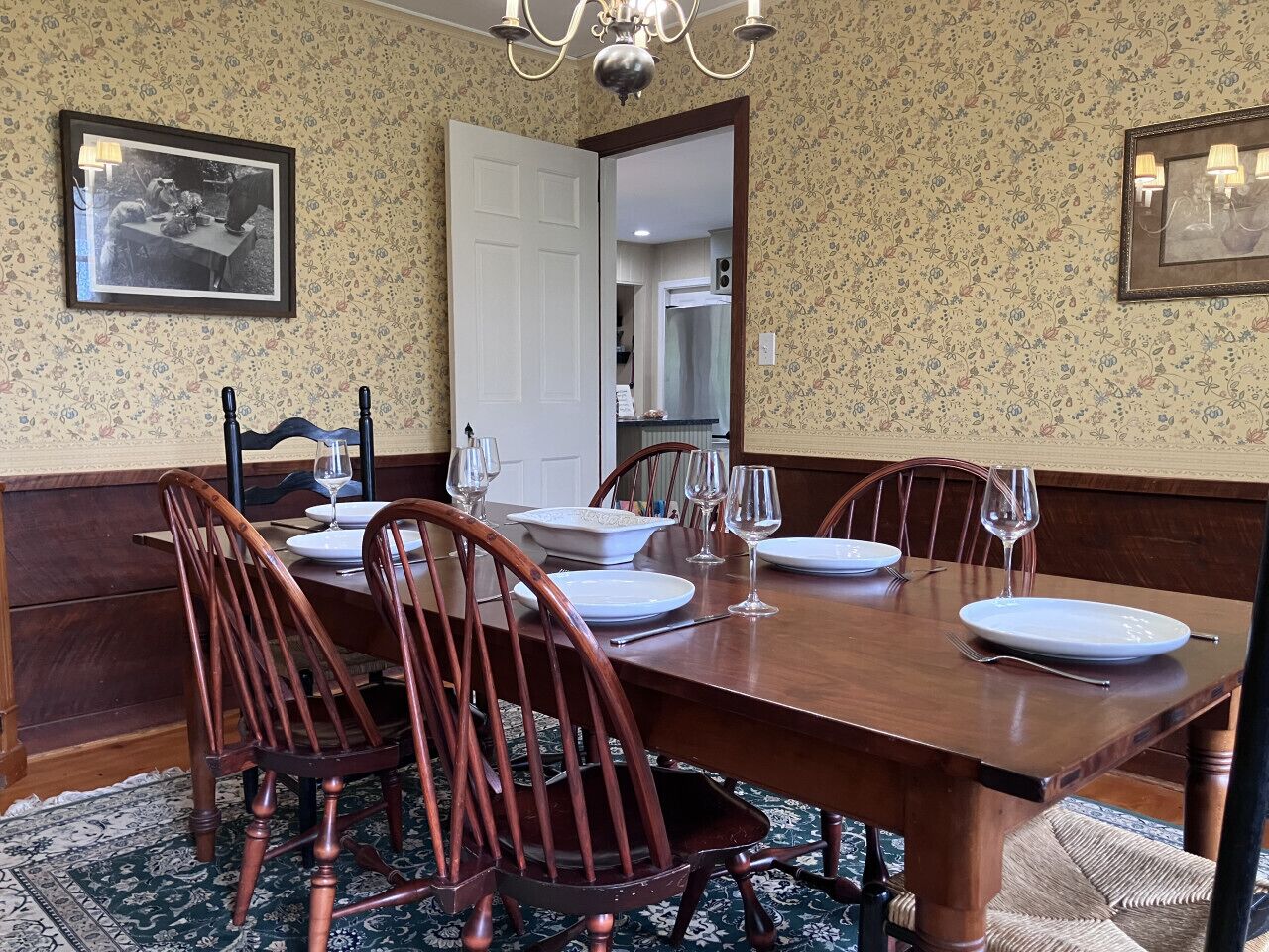Een eetkamer met een houten tafel voor zes personen, omringd door houten stoelen.