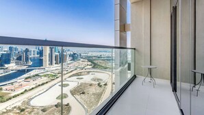 A balcony with a glass railing overlooking a cityscape with modern buildings and a river.