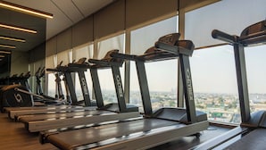A gym with treadmills labeled 'Intelligent Suspension' and a view of a cityscape through large windows.