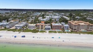 Vista aérea de una zona costera con playa, varios edificios y un puerto deportivo.