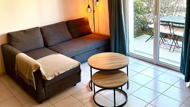Een moderne woonkamer met een bank, een ronde houten tafel en een hanglamp.