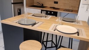 A modern kitchen with a central island, two bar stools, a microwave, and a sink.