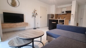 A modern living room with a flat-screen TV, a blue sofa, and a round coffee table.