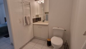 A compact bathroom with a toilet, sink, and towel rack.