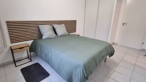 A bedroom with a bed, bedside tables, a nightstand, a radiator, and a door.