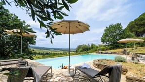 A poolside area with lounge chairs, umbrellas, and a stone patio. - In The Heart Of Chianti Pool Wifi View  (Castellina in Chianti)