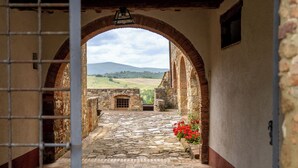 A stone pathway leading through an arched doorway to a scenic landscape. - In The Heart Of Chianti Pool Wifi View  (Castellina in Chianti)