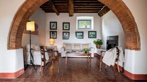 A cozy living room with a brick archway, a white sofa, a wooden coffee table, and a lamp. - In The Heart Of Chianti Pool Wifi View  (Castellina in Chianti)