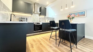 A modern kitchen with dark cabinetry, a central island with bar stools, and a dining area.