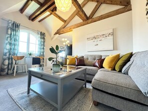 A living room with a grey sofa, a coffee table with a plant, a window with curtains, and a painting on the wall. - The Accommodation - Cumbria, UK (Ulverston)