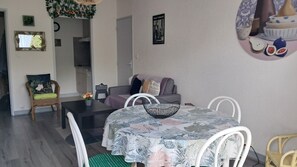A modern living room with a dining table, a sofa, and a chair. There is a small table with a vase of flowers. - Apartment near the beach (Villers-sur-Mer)