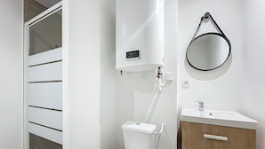 A bathroom with a toilet, a sink, a mirror, and a window. - Bright 1-bedroom apartment (Cuxac-d'Aude)