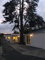 A row of small, single-story cabins with open front doors, each with a light source visible through the door.