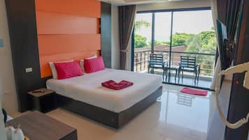 A modern hotel room with a large bed, a small desk, and a balcony with outdoor seating.