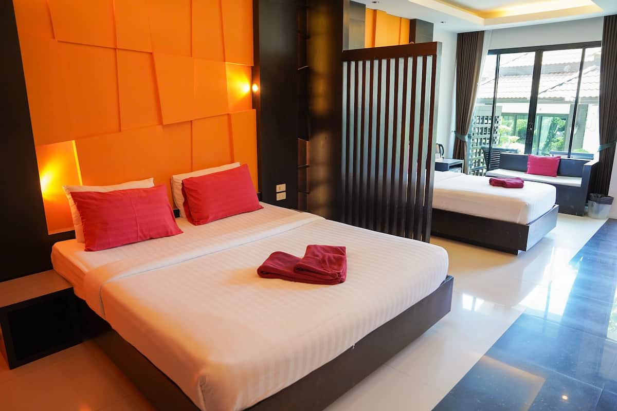 Una habitación de hotel moderna con una cama grande, un sofá más pequeño, un balcón con vistas y una puerta corredera.
