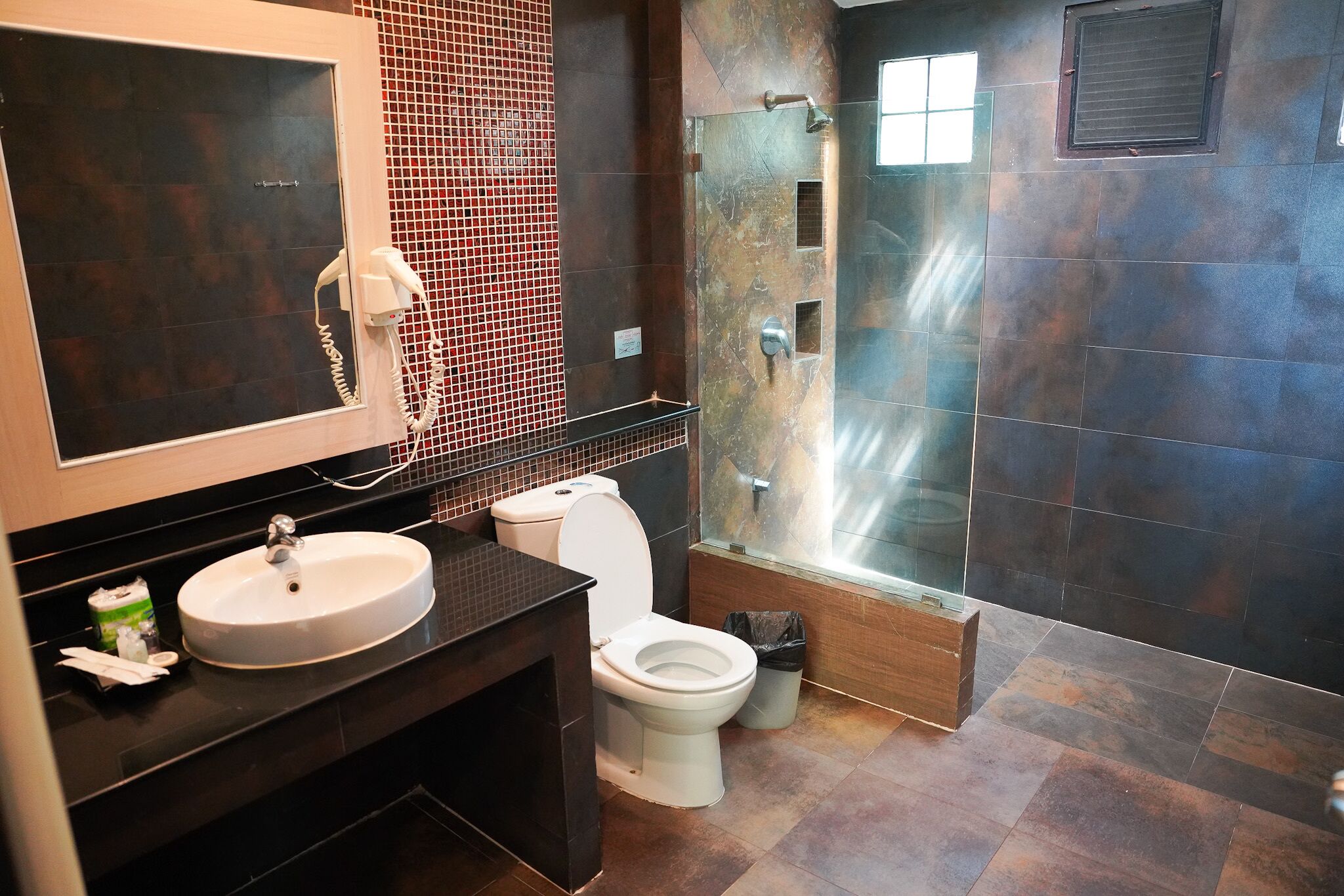A modern bathroom with a large mirror, a sink, a toilet, and a shower area.