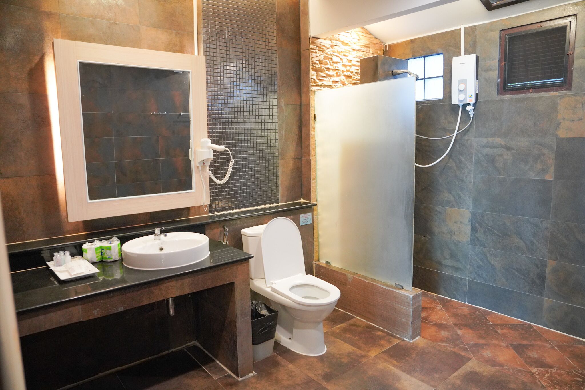A modern bathroom with a large mirror, a sink, a toilet, and a shower area.