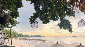 Ein Restaurant direkt am Strand mit Außenplätzen, Sonnenschirmen und Meerblick.