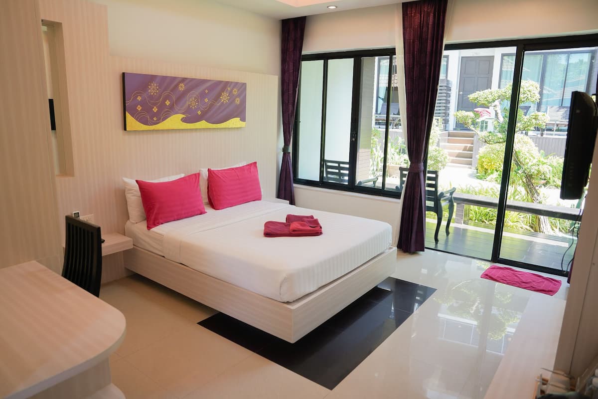 Habitación de hotel moderna con una cama grande, una pequeña mesa y vistas al balcón exterior.