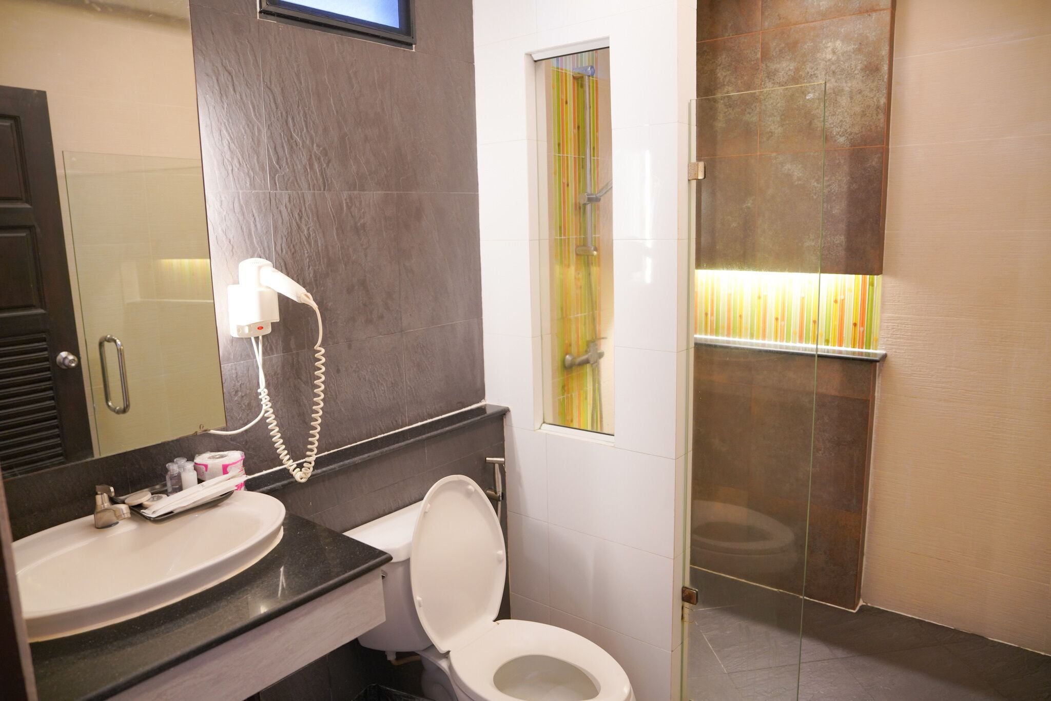 Un baño con lavamanos blanco, inodoro y ducha con mampara de vidrio.