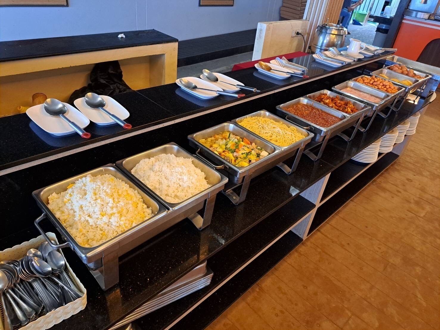 A buffet line with various food options, including rice, pasta, and different sauces.