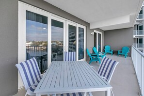 A balcony with a table and chairs, a view of the city, and a building with a grey facade. -  3rd floor 326 Newly Remodeled  Panama City Beach (Panama City Beach)