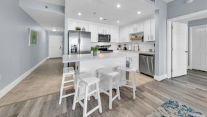 A modern kitchen with white cabinets, stainless steel appliances, and a central island with bar stools. -  3rd floor 326 Newly Remodeled  Panama City Beach (Panama City Beach)