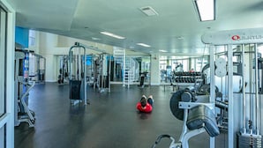 A gym with various exercise equipment, a person lying on a red mat, and a staircase leading to an upper level. -  3rd floor 326 Newly Remodeled  Panama City Beach (Panama City Beach)