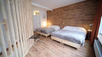 Un dormitorio con dos camas, una pared de madera y un radiador.