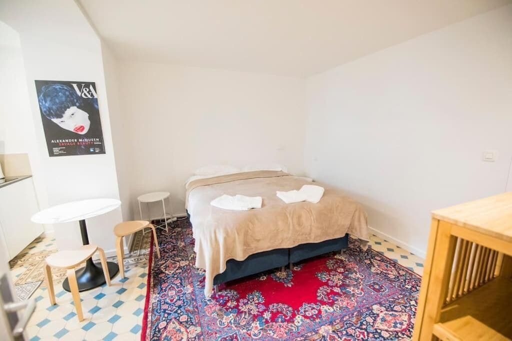A small, neatly arranged room with a bed, a small table, and a chair.
