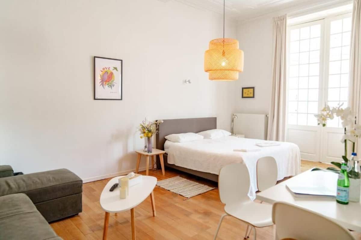 A modern bedroom with a bed, bedside table, chair, and a hanging light fixture.