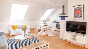 A modern living room with a white sofa, a dining table, and a TV. - Smart Appart Gare Du Midi (Brussels)