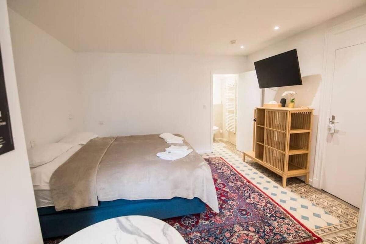 A bedroom with a bed, a TV mounted on the wall, and a wooden cabinet.