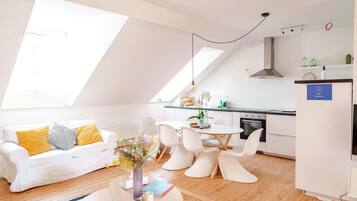 Un apartamento moderno con comedor, cocina y un sofá blanco con cojines amarillos.