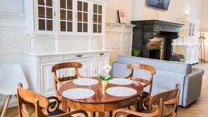 A dining area with a wooden table and chairs, a white cabinet, and a fireplace. - Smart Appart Gare Du Midi (Brussels)