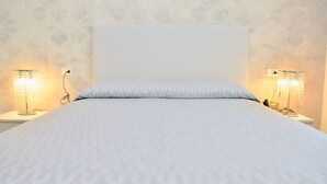 Una cama bien tendida con un edredón estampado, dos lámparas de noche y un cabecero sencillo.