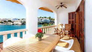 A balcony with a wooden table, white chairs, and a potted plant. - Casa Michaela, House 5StarsHome Mallorca. (Porto Petro)