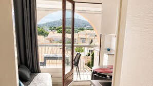 Un balcon étroit avec un canapé, une table à manger et une vue sur un quartier résidentiel.