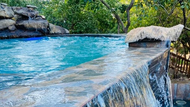 Una piscina con cascata, immersa in un paesaggio naturale.